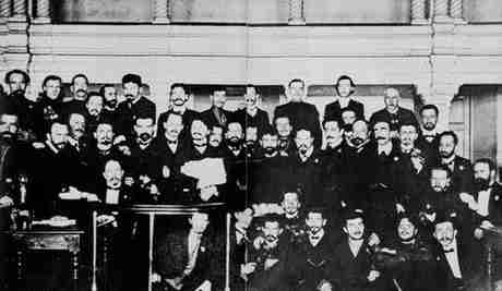 Ο Τρότσκι (με τον φάκελο στα χέρια) μεταξύ των μελών του σοβιέτ της Αγίας Πετρούπολης, το 1905, κατά την διάρκεια της δίκης τους